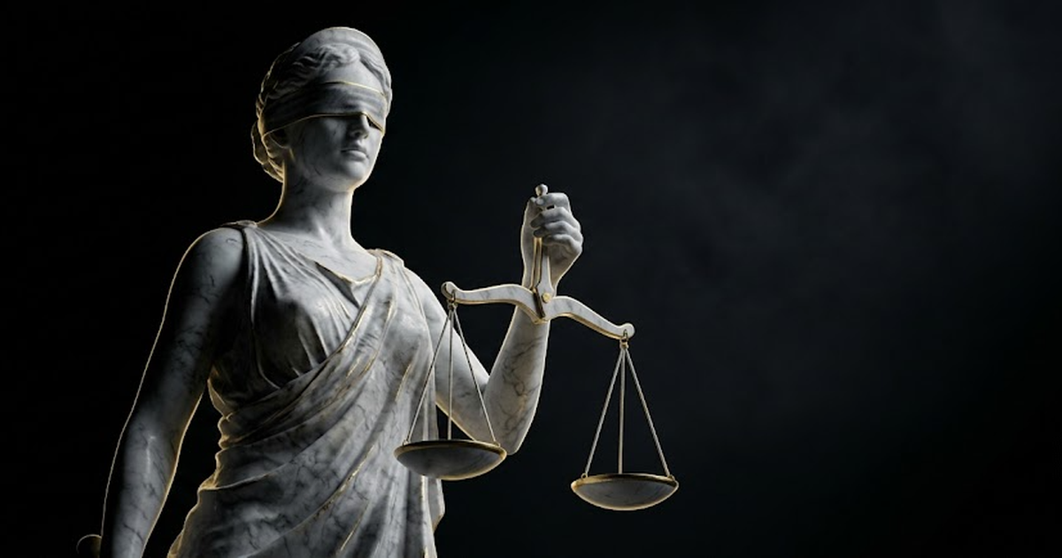 A colossal marble statue of Themis holding balanced scales in near darkness lit by gold light