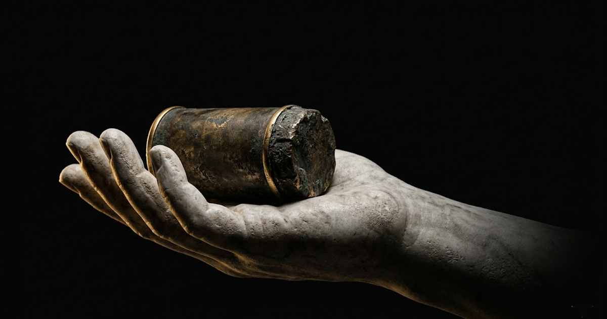 A classical marble hand cradling a small sealed bronze cylinder against a void black background, lit by a single gold rim light.