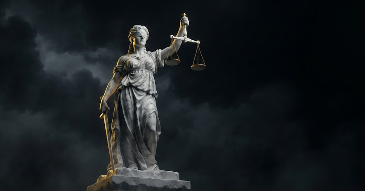 A towering marble statue of the goddess Themis holding scales, lit by gold light against a black void
