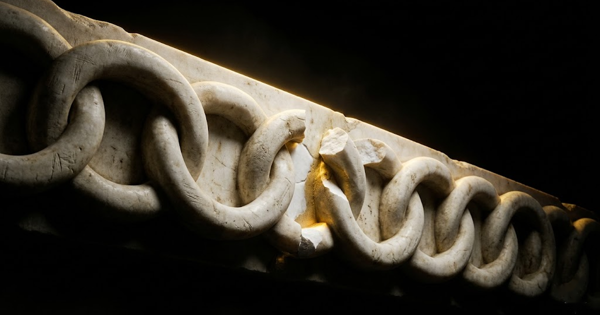 A marble relief of an interlocking chain with one link visibly fractured, lit by gold rim light against void black.